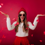 joyful-long-haired-girl-in-knitted-hat-having-fun-in-valentine-s-day-good-looking-brunette-lady-in-white-sweater-standing-under-heart-confetti