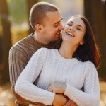 Happy couple in cozy sweaters hugging outdoors, reflecting the warmth of finding love with Step2Love.
