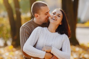 Happy couple in cozy sweaters hugging outdoors, reflecting the warmth of finding love with Step2Love.