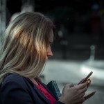 Woman in a blue blazer using her smartphone outdoors.