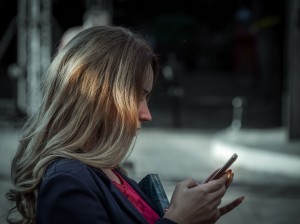 Woman in a blue blazer using her smartphone outdoors.